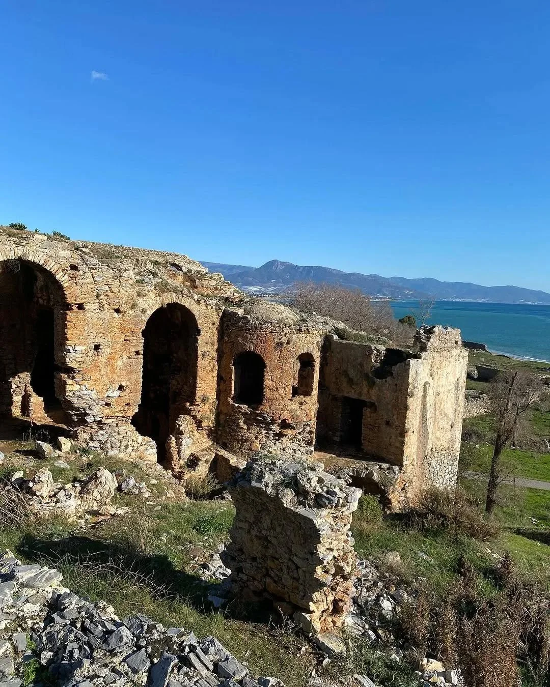 Tarih ve Doğa: Deniz Manzarasıyla Çevrili Antik Kalıntılar! Deniz manzarasıyla çevrili, yıpranmış antik kalıntılar ve yeşil bitkiler