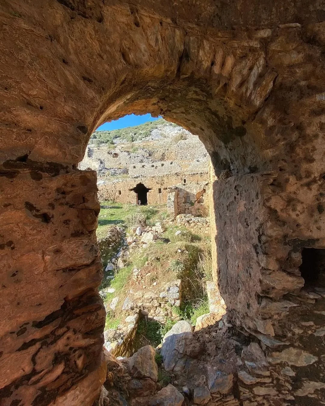 Anemurium'un Tarihi Kemerleri! Taş yapılar ve mavi gökyüzü birleşimi Taş kemer yapısı, arka planda kalıntılar ve yeşil alan ile mavi gökyüzü