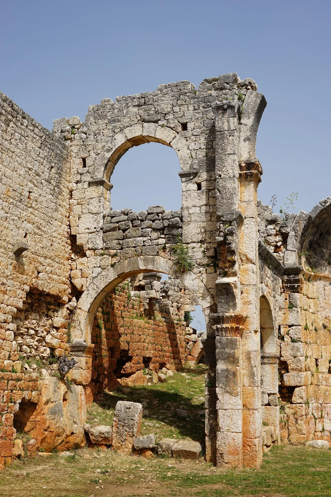 Eski yapının kalıntıları, yeşilliklerle çevrili taş duvarlar ve büyük kemerler.