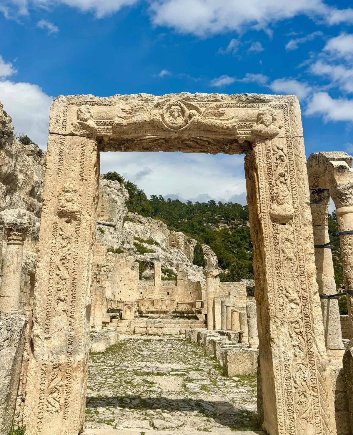 Alahan Manastırı'nın Büyüleyici Kalıntıları - Taş kapı sütunu ve yeşil ağaçlar İşlemeli taş kapı sütunu ve arka planda yeşil ağaçlarla kaplı kalıntılar