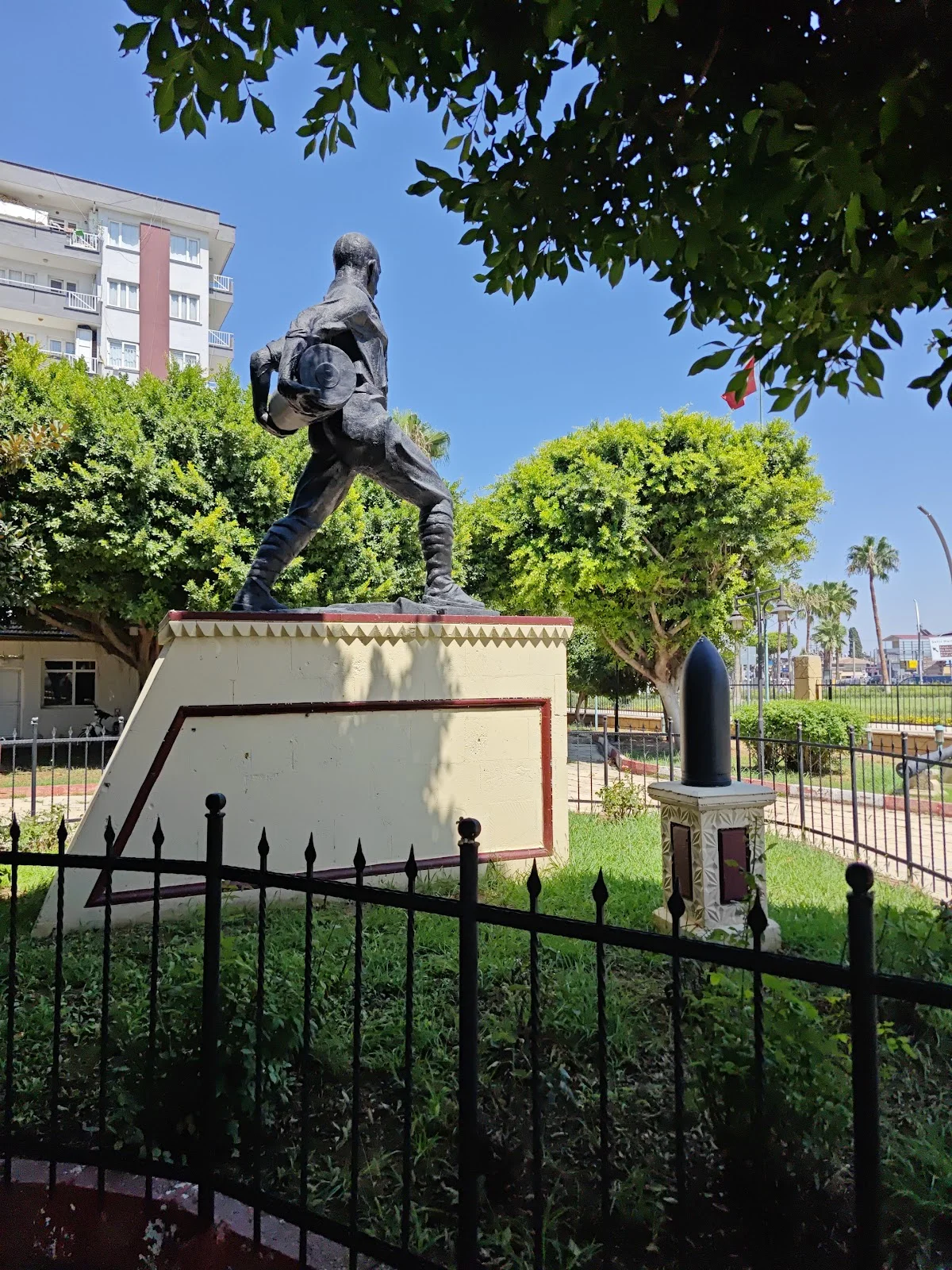 Nusrat Mayın Gemisi Heykeli - Sanat ve Şehir Bir Arada! Sırtında çanta taşıyan dinamik bir heykel, yeşil çim ve modern apartmanlar arasında yer alıyor.
