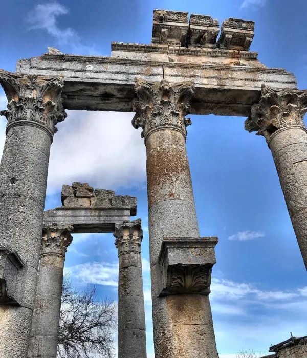 Antik yapıya ait yüksek kolonlar ve mavi gökyüzü arka planda