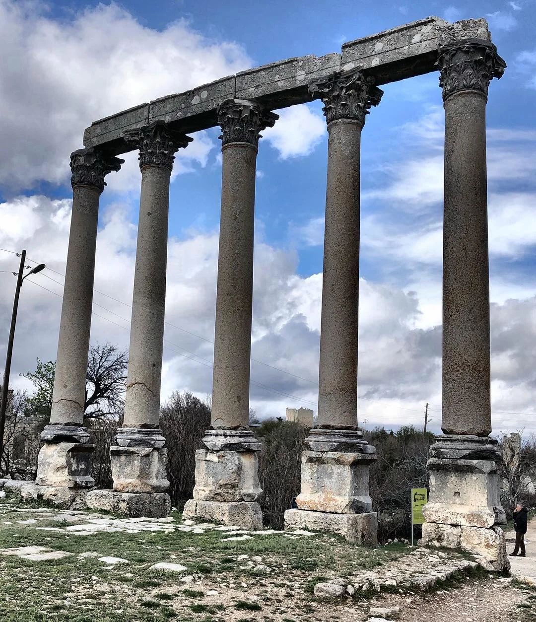 Doğal Atmosferde Tarihi İzler - Antik Kalıntılar ve Gökyüzü! Antik sütun kalıntıları, bulutlu gökyüzü ve yeşil zemin ile doğal bir atmosfer oluşturuyor.
