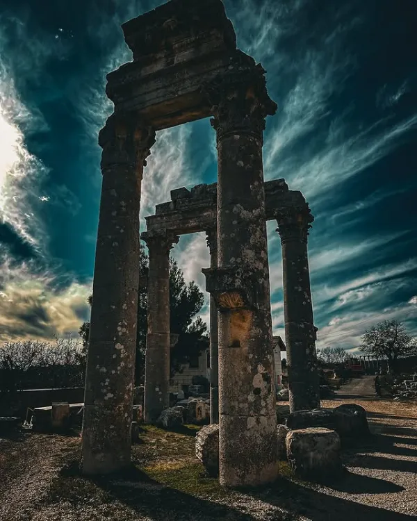 Eski yapının kalıntıları, büyük sütunlar ve dramatik gökyüzü ile mistik bir atmosfer sunuyor.
