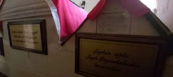 Zeyne Türbesi'nde yer alan iki bilgi levhası ve arka plandaki dekoratif unsurlar.