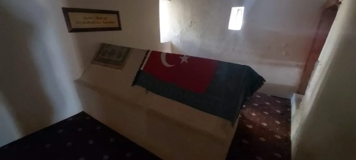 Zeyne Türbesi'nin İç Mekan Detayları - Sade Tasarım ve Kültürel Derinlik! İki örtü ile kaplanmış mezar, Türk bayrağı ve desenli örtü ile süslenmiş.
