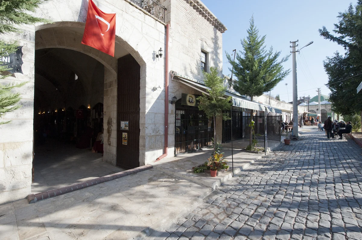 Tarihi ve Turistik Durak - Kırkkaşık Bedesteni'nin Canlı Atmosferi! Tarihi Kırkkaşık Bedesteni'nde kalabalık taş döşeme, taş yapılar ve dalgalanan Türkiye bayrağı