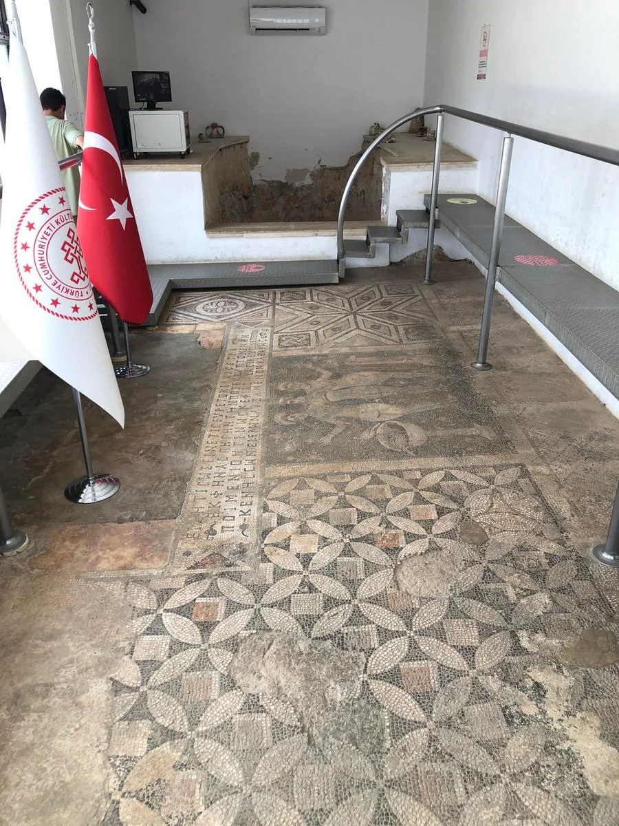 Tarihî Güzellikler: Modern Müze İçinde Geometrik Mozaikler Modern bir müze iç mekanında çeşitli geometrik desenlere sahip tarihî mozaikler ve yazılı metinler