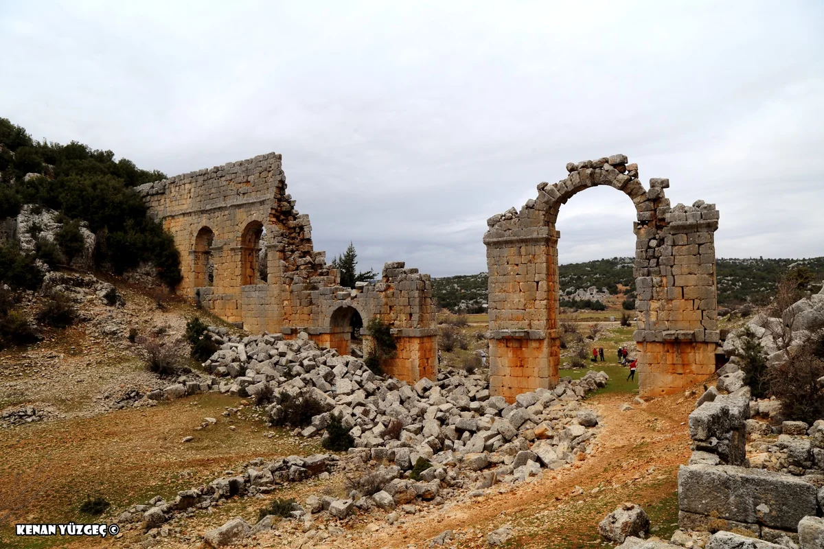 Olba Antik Kenti'nin Gizemi - Tarihin İzlerini Keşfetmeye Var mısınız? Tarihi kalıntılar, yıkılmış taş yapı ve çevresinde devrilmiş taşlar.