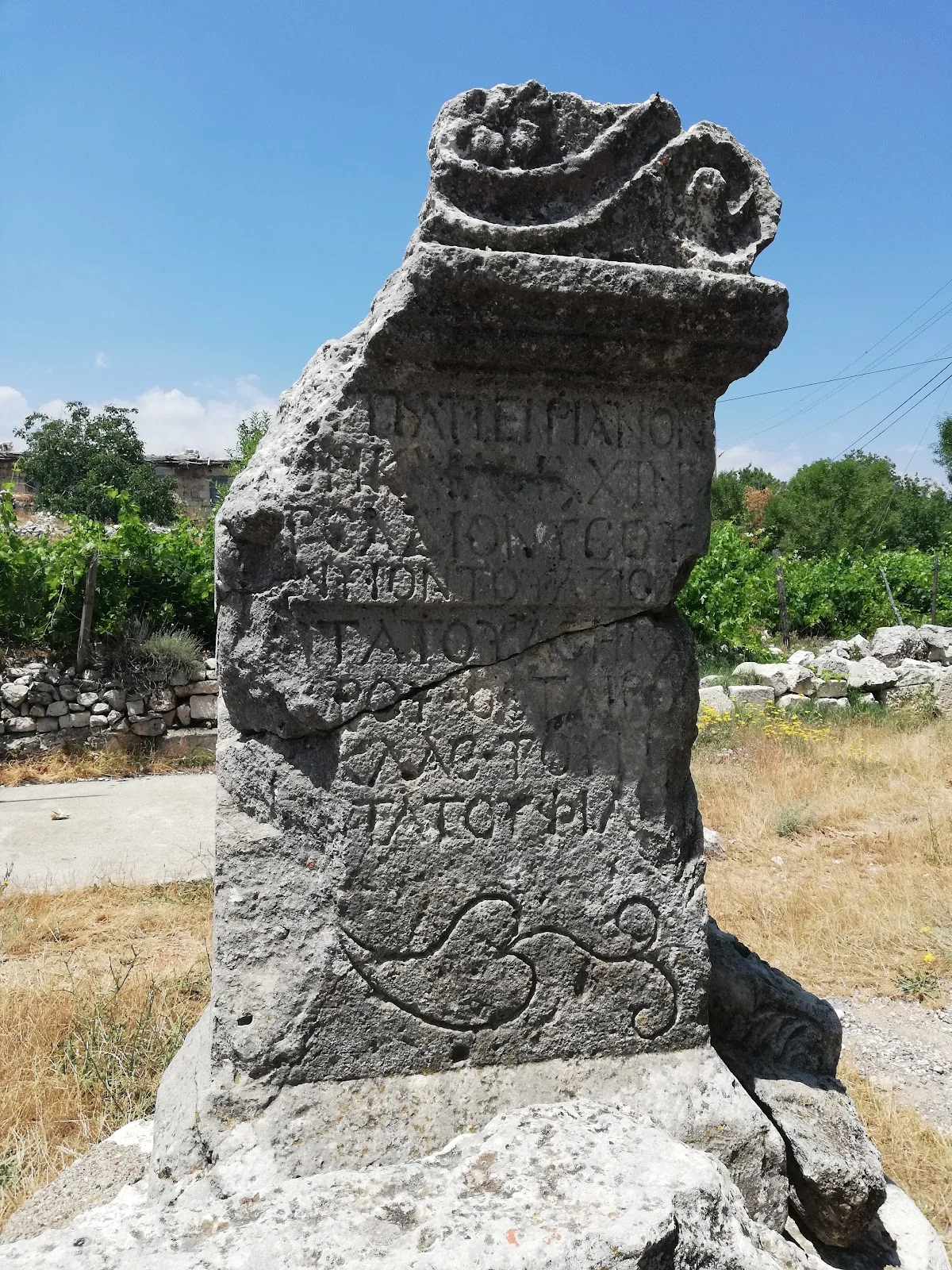 Olba Antik Kenti'nin Büyüleyici Kalıntıları - Tarihin Derinliklerinde Bir Yolculuk! Taş sütun ve arka planda diğer antik kalıntılar, açık mavi gökyüzü ile çevrili.