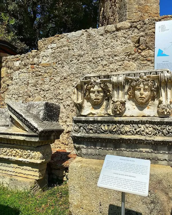 Antik yapı kalıntıları, taş sütun başlıkları ve Medusa figürü görünmekte.