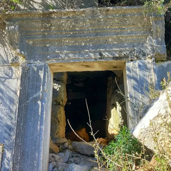 Eski taş yapının girişi, doğa ile birleşmiş gizemli bir atmosfer sunuyor.