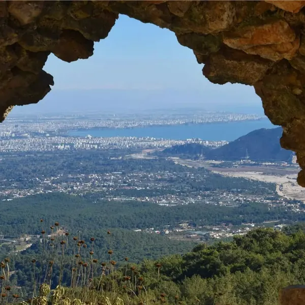 Yeşil orman dokusunun önünde, deniz ve şehir manzarasıyla Trebenna Antik Kenti panoraması