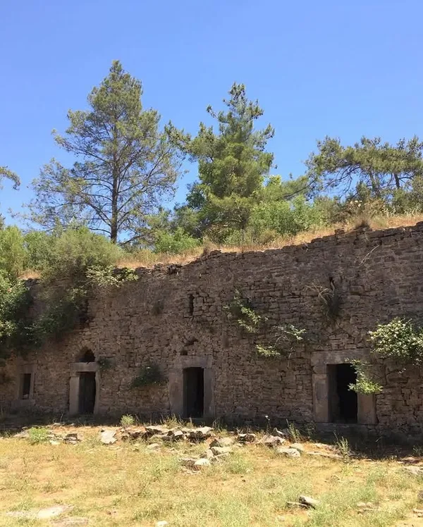 Eski taş yapının kalıntıları, yeşillikler ve ağaçlarla çevrili