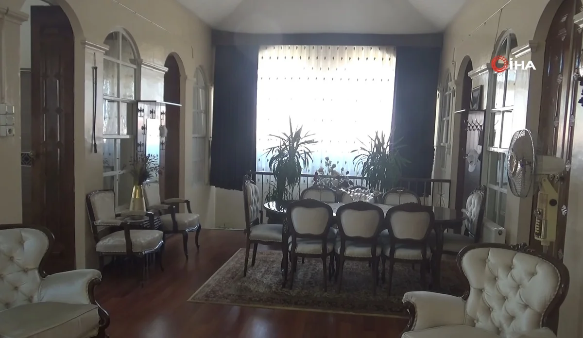 Geniş, aydınlık bir oturma odasında yuvarlak masa ve şık sandalyeler yer alıyor.