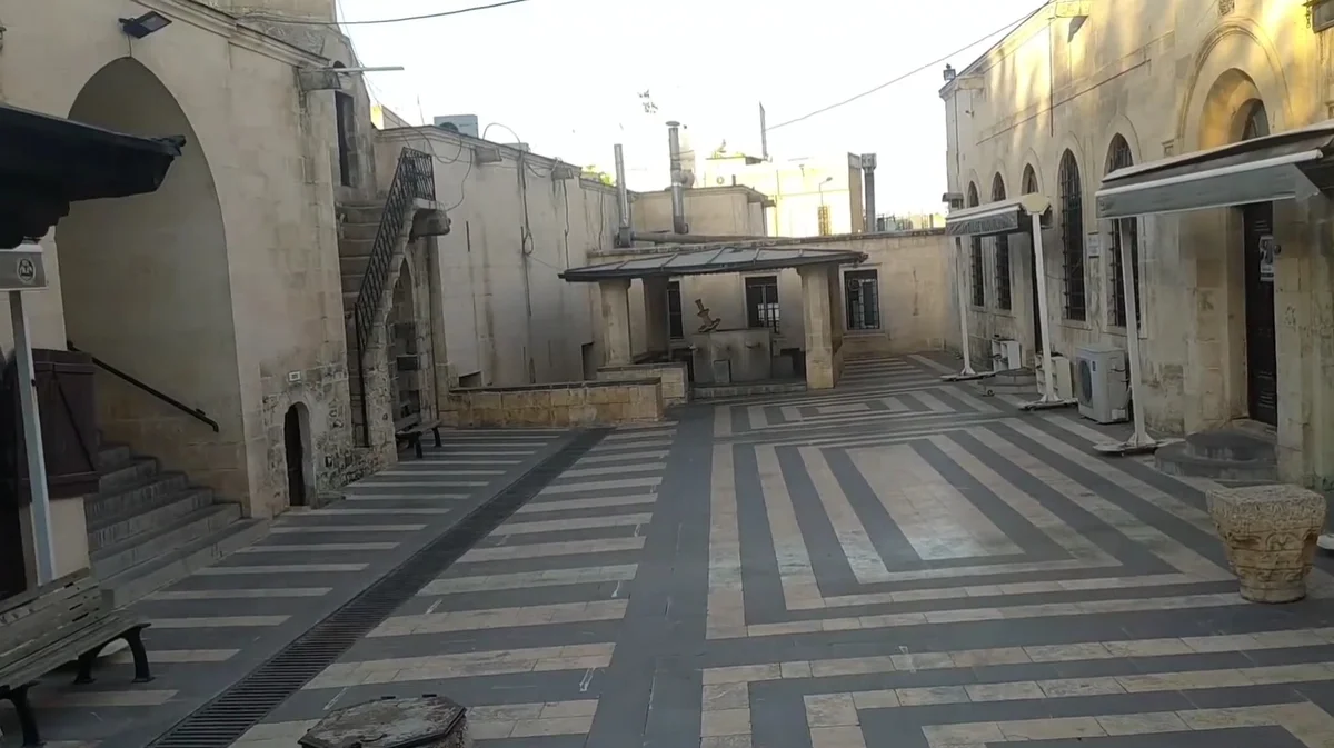 Taş yapılarla çevrili tarihi avluda merdiven ve pencereler görünmekte.