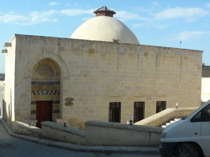 Taş duvarlarla inşa edilmiş tarihi hamam, büyük bir kubbe ve detaylı kapıyla dikkat çekiyor.