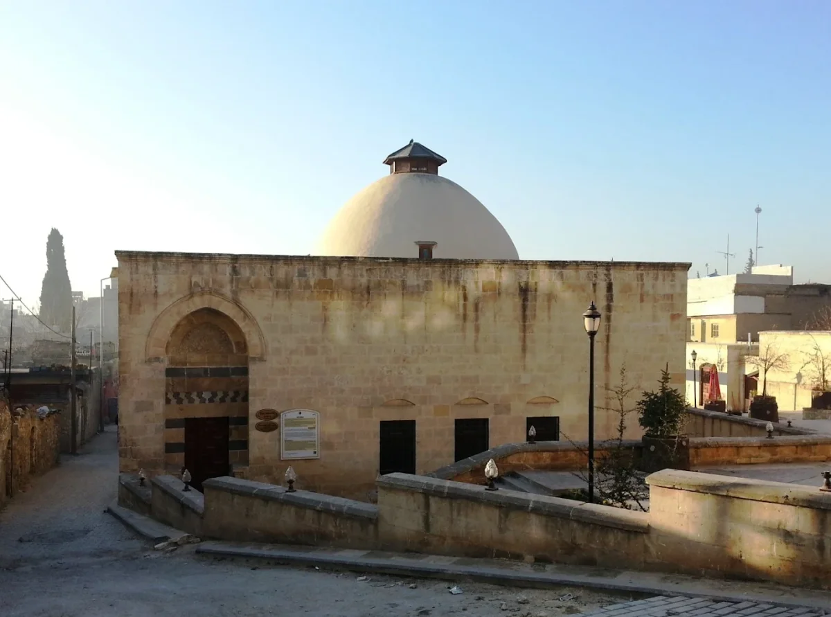 Taş malzemeden yapılmış tarihi hamam, büyük kubbe ve merdiven ile çevresinde ağaçlar var.