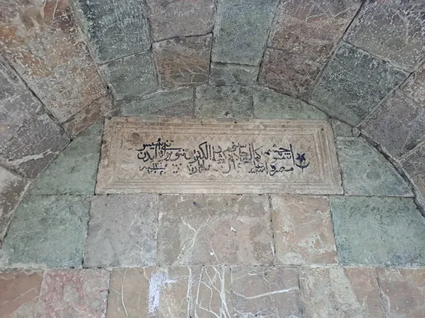 Taş kemer altındaki detaylı Arap harfli kitabe ve süslemeler