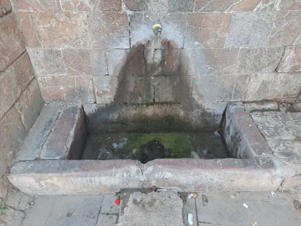 Eski taş yapıda musluktan akan su ve yosun kaplı taşlar